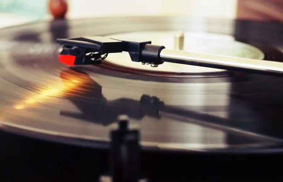 Detailed view of a spinning vinyl record on a turntable with a stylus playing the music.