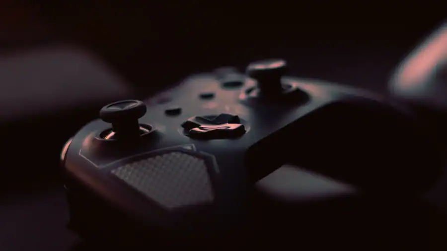 A close-up shot of a game controller in low light, highlighting its design and buttons.