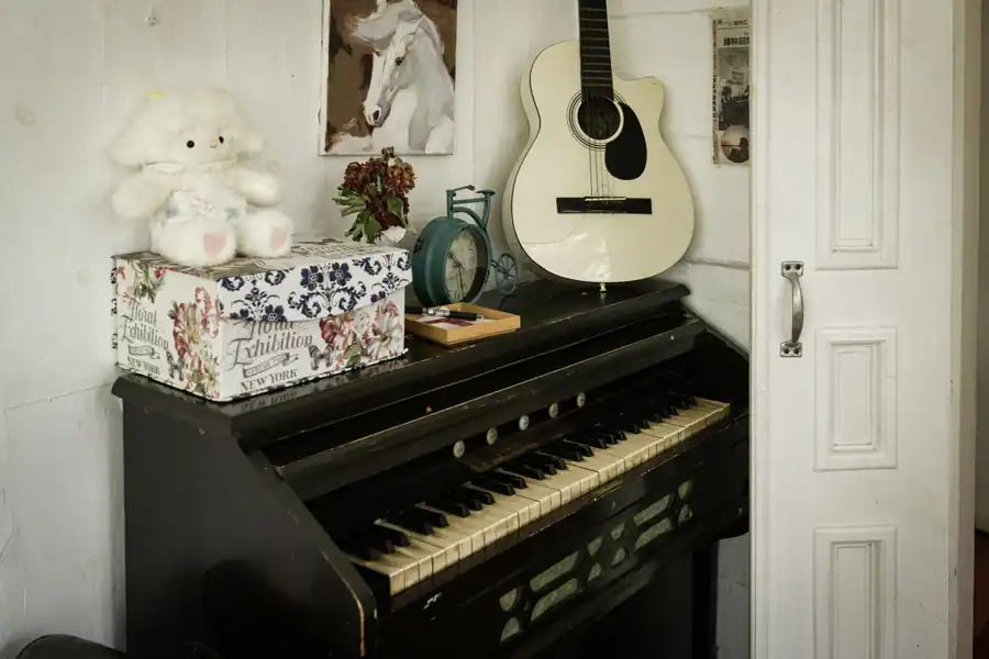 Interior featuring a vintage piano, guitar, and decor items for a cozy ambiance.