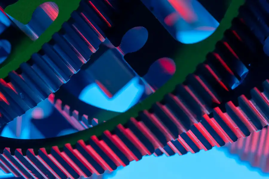 Vibrant close-up of interlocking gears illuminated with colorful lights, showcasing industrial precision.