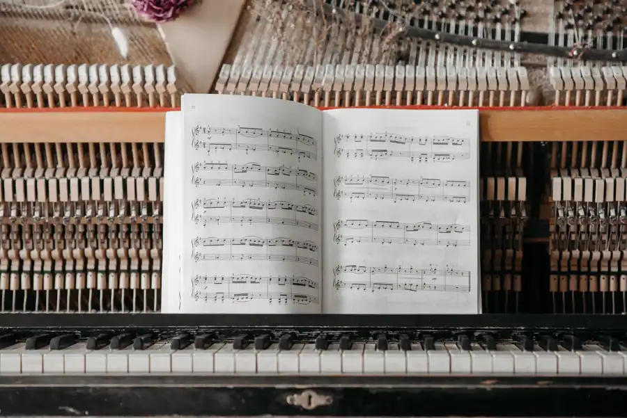 Detailed view of piano internals with sheet music placed on keys, showcasing the intricate mechanics.