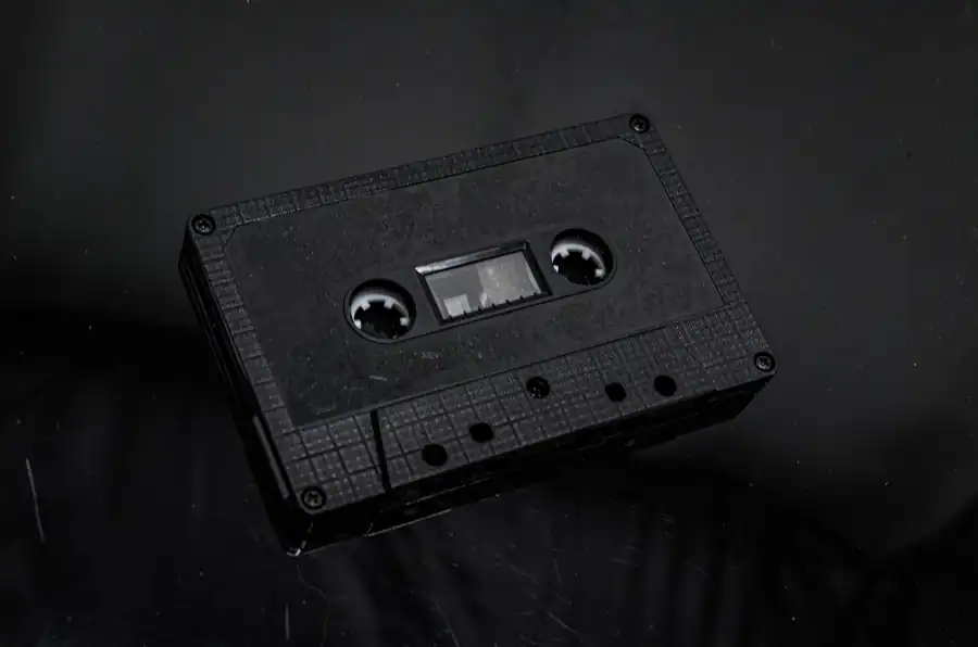 Close-up of an old cassette tape on a dark surface, evoking nostalgia.