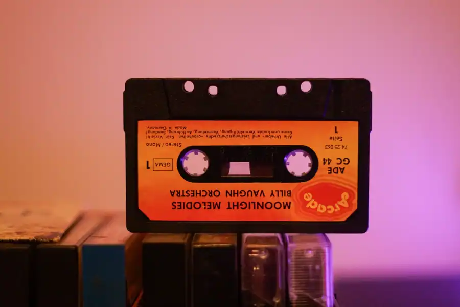 Retro orange cassette tape from Billy Vaughn Orchestra stacked on a shelf under warm lighting.